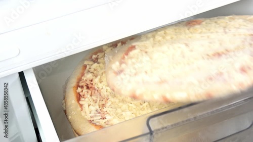 male hand getting a frozen pizza from refrigerator drawer