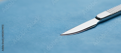 Sterile scalpel blade close-up on blue surgical cloth in a medical environment