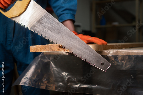 Photos Close-up of carpenters hand saw cutting wood board working in carpenter shop