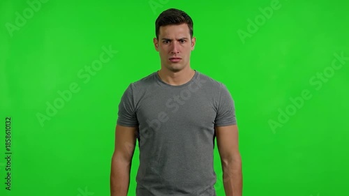 Man with serious expression on green screen looking directly at camera.