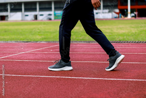 Person walking on a running track with athletic shoes and sportswear