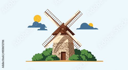 Traditional stone windmill with wooden sails standing in a field of green bushes under a clear sky with a sun.