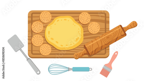 Overhead view of a delightful baking scene with cookie dough, various cookies, a rolling pin, spatula, whisk, and brush on a wooden board.