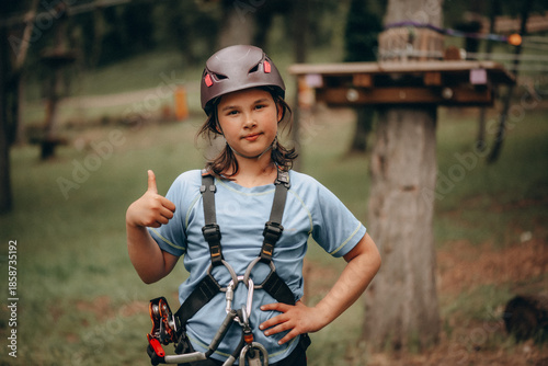 Confident Girl Giving OK Sign in Safety Harness at Adventure Park
