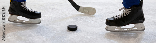hockey puck lies adjacent worn skate blade weathered ice aging indoor ice rink surface bathed soft