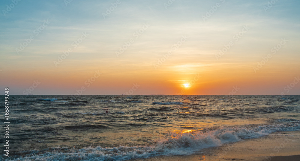 Obraz premium serene panorama image capture beauty sunset over calm ocean. sun low on horizon casting warm golden glow across sky and reflect off gentle wave. warm orange near creating peaceful calm atmosphere.