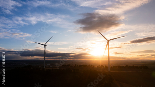 Wind Turbines Silhouetted at Sunrise Over Vast Rural Fields
