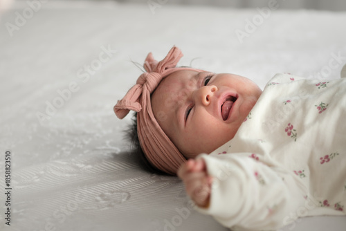Upset Newborn Baby Girl Crying on White Bed.
