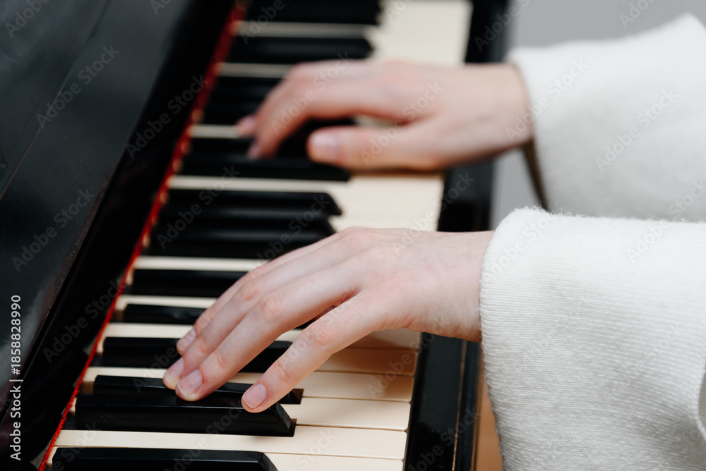 Obraz premium female pianist hands on black and white piano keyboard, close-up view, young woman playing piano, professional musician