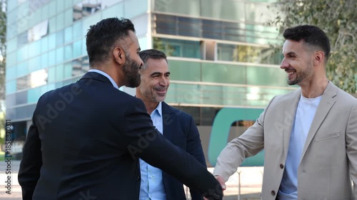 Three professional men shaking hands after agreement deal in front of modern office building