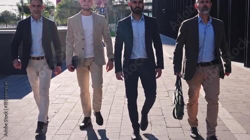 Four confident Hispanic, Middle Eastern and Indian businessmen walking in the city going to work