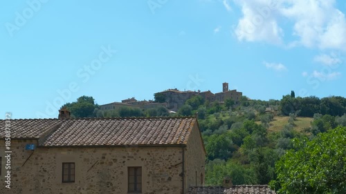 Scenic italian landscape with medieval village on hilltop. Beautiful tuscan countryside with a historic medieval village nestled on a lush green hill under a clear blue sky, showing architecture