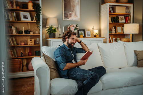 Bild auf Leinwand Happy man relaxing on sofa reading book at home