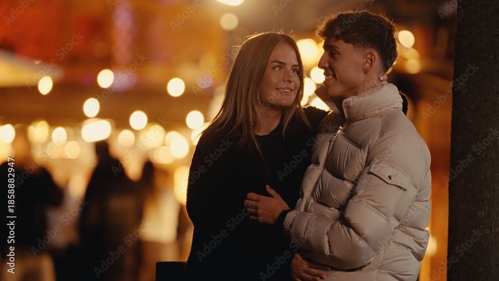 Fototapeta premium A young couple embraces in Paris at night surrounded by bokeh lights The image captures a romantic moment between a man and woman in love during a city break suitable for travel and lifestyle content.