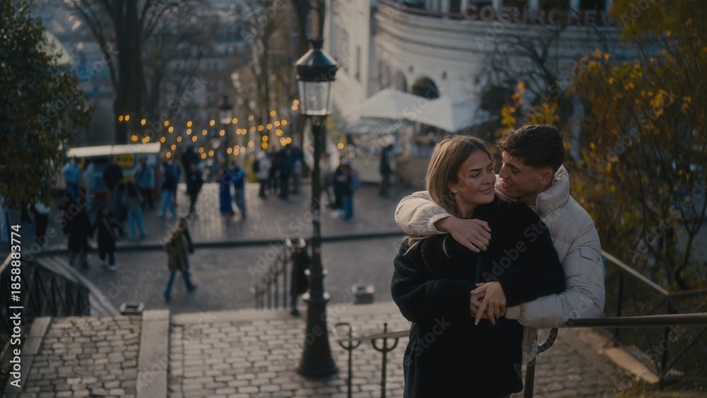 Obraz premium A romantic couple embraces in Montmartre Paris France with a cityscape view in the background. This image is perfect for travel tourism and lifestyle content showcasing love and affection in an urban 