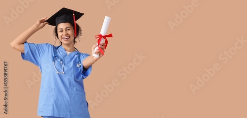 Female African-American medical student in graduation hat and with diploma on...