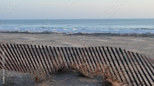 Snow fence along a Lake Michigan beach to slow the wind and drop the blowing sands.  Ice is piling up along the coast in this winter scene.  Point Beach State Forest, Wisconsin.