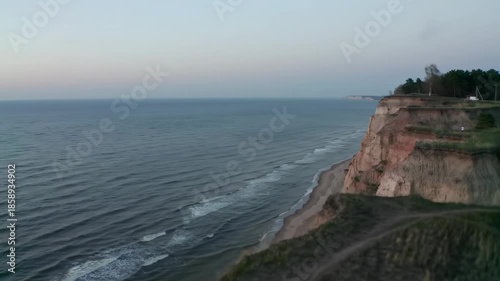 A coastal scene with cliffside, ocean, and fading sky
