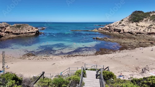 A wooden staircase descends toward Diamond Bay in Sorrento, Victoria, Australia, with rugged coastal cliffs and clear blue ocean water. Australian shoreline and attractions with rock formations.