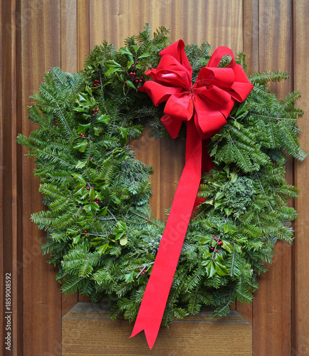 Decorative Christmas wreath made of natural evergeen branches on wood grain door