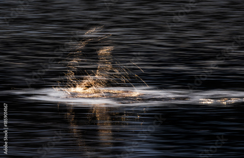Abstract long exposure water light trails and golden splash on dark lake creating cinematic portal illusion motion blur reflections and minimalist fine art mood of time and transformation at dusk