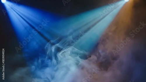 Stage lights illuminate smoke in a dark setting.