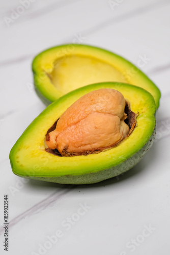 A slice of fresh avocado on a white plate on a marble table top view