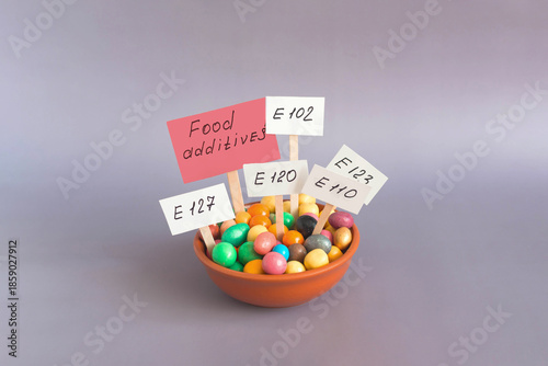 A container filled with colored granules of food additives and information signs with inscriptions