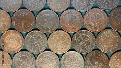 A collection of old coins arranged in a pattern, showcasing various shades of brown and copper, with inscriptions and dates visible
