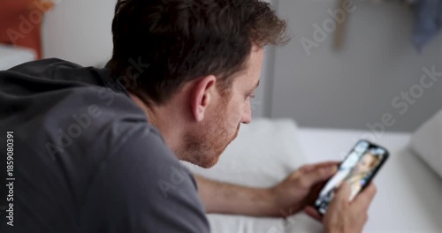 guy doom scrolling through social media or waiting for a message. Alone in bedroom, staring at smartphone. emotional distance psychological strain. Smartphone addiction. Digital overload, loneliness.