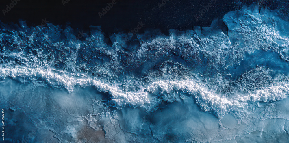 Fototapeta premium Waves crash on the shore during twilight with a dark sky above the ocean surface