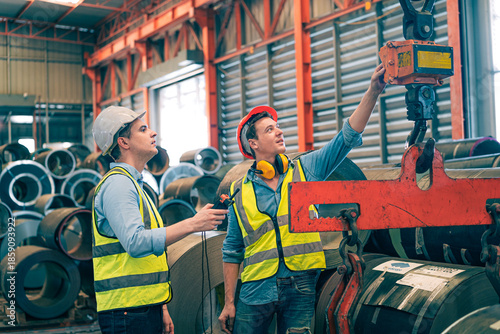 Billede på lærred Caucasian industrial engineer men controlling overhead crane with remote in factory