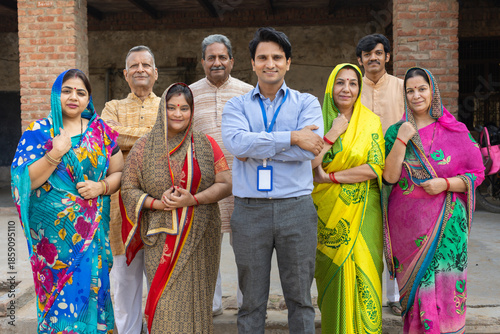 Bank executive or finance person standing with group of rural indian men and women standing at camera. People of india.