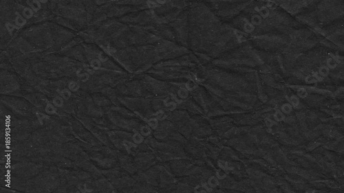 Textured black paper surface with crinkled folds creating a dark grungy and abstract background