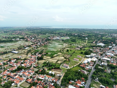Wide aerial view of suburban town with red roof houses blending into green farmland landscape