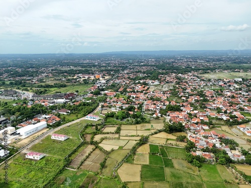 Wide aerial view of suburban town with red roof houses blending into green farmland landscape