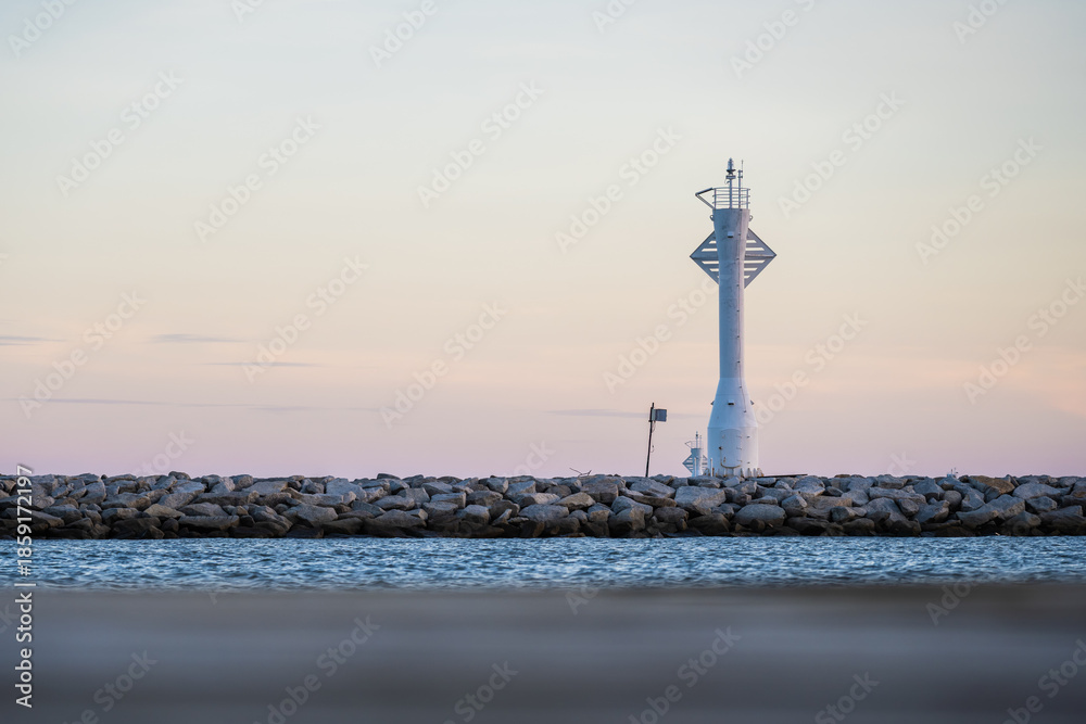 Fototapeta premium Minimal Lighthouse on Breakwater at Calm Sea and Pastel Sky