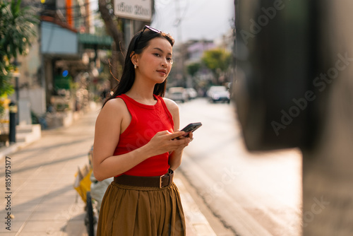 Photography Asian woman texting on smartphone in city street, engaging with technology