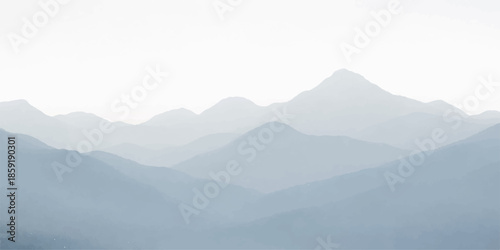 A breathtaking morning view of a misty mountain landscape at sunrise, where the sun illuminates the fog and blue clouds over a snow-covered forest valley and rolling hills on the nature horizon