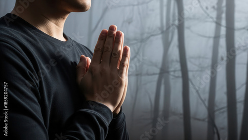 Woman in black top doing breathing exercises with hands in prayer position, enveloped by dense fog in a tranquil forest setting, emphasizing mindfulness and calm