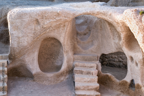Uchisar Castle, Cappadocia, Turkey. Ancient rock-cut dwellings with carved arches, openings, and steps in light-colored stone