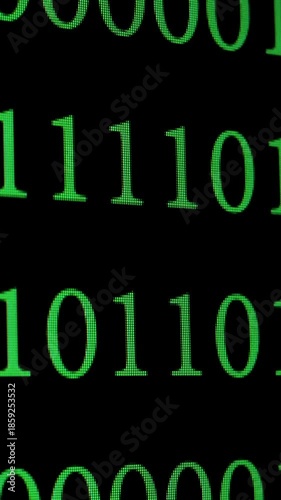 An enlarged image of green binary code (ones and zeros) on a black digital screen, symbolising programming, data encryption and cybersecurity, vertical footage