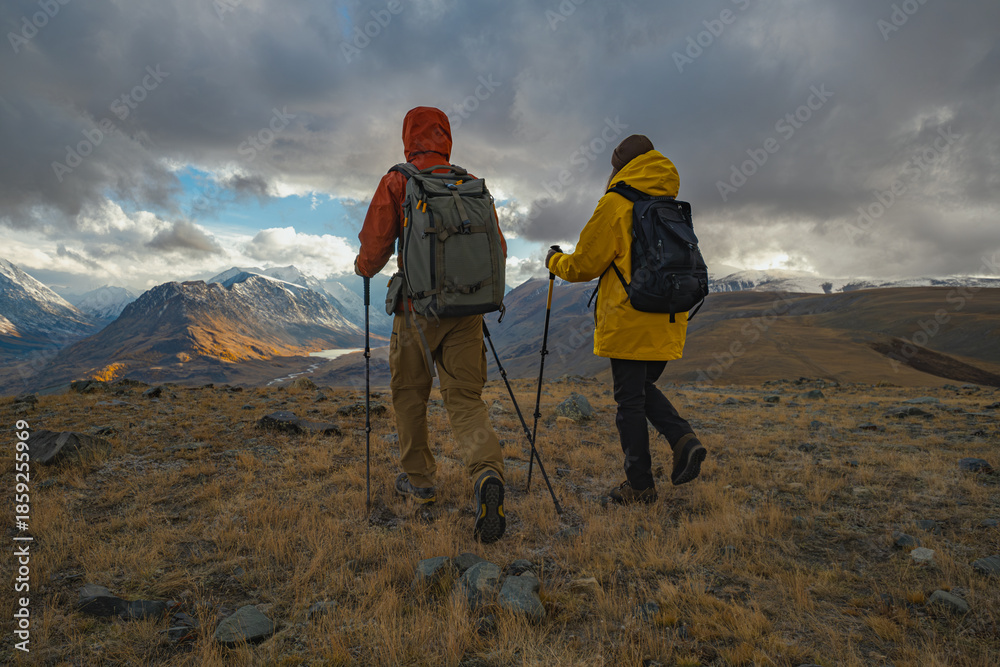 Ταπετσαρία A couple with backpacks and trekking poles stand on a hilltop, gazing into a distant valley during autumn's golden hour