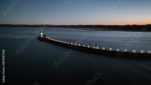 Wallpaper Mural Aerial footage of green-and-white lighthouse standing at  end of  long pier with illuminated Christmas tree. Lighthouse on Nordmole at Travemunde at Baltic Sea in winter. Camera pan from right to left Torontodigital.ca