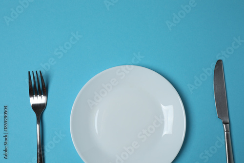 Panel kuchenny z motywem Empty plate and cutlery on colored background, top view 