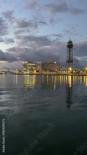 Barcelona harbor at dusk with city lights and reflections on calm water
