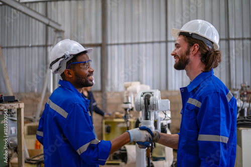 Blue collar workers are working at machine shop with welding robot arm.