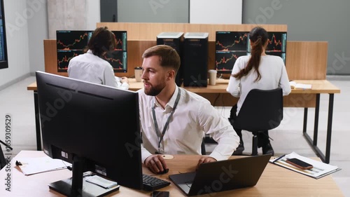By the table, sitting. Business people are working with stock market exchange in office
