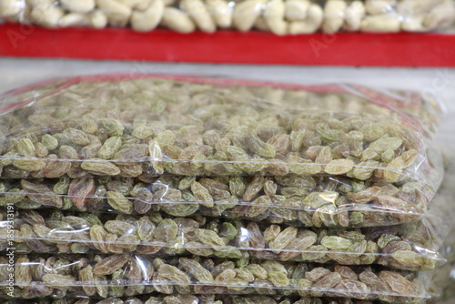 Stacked clear plastic bags of green raisins (kishmish).
