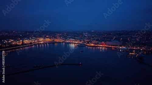 Aerial view of city lights reflecting on the water in the dark, creating a striking contrast, Rade of Geneva, Geneva, Switzerland.
